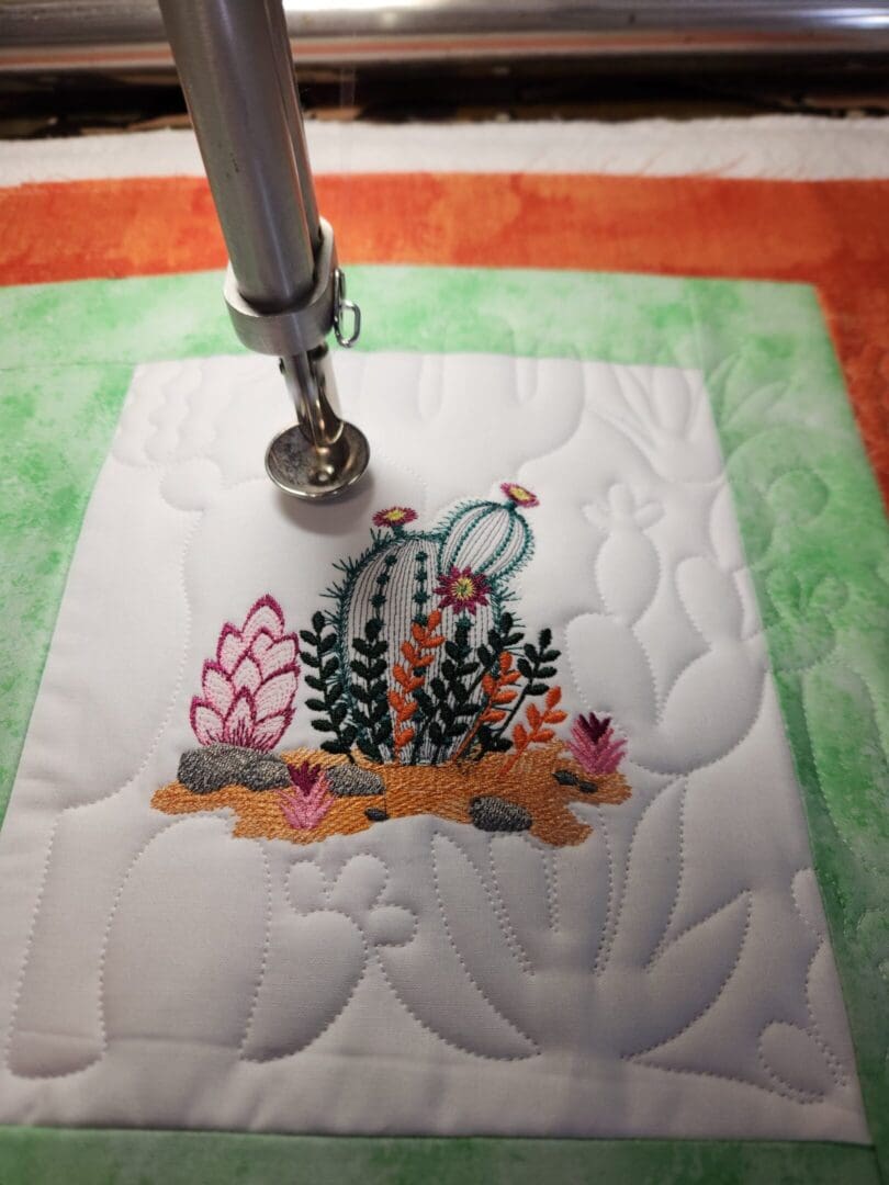A close-up of a sewing machine stitching a colorful underwater scene on fabric.