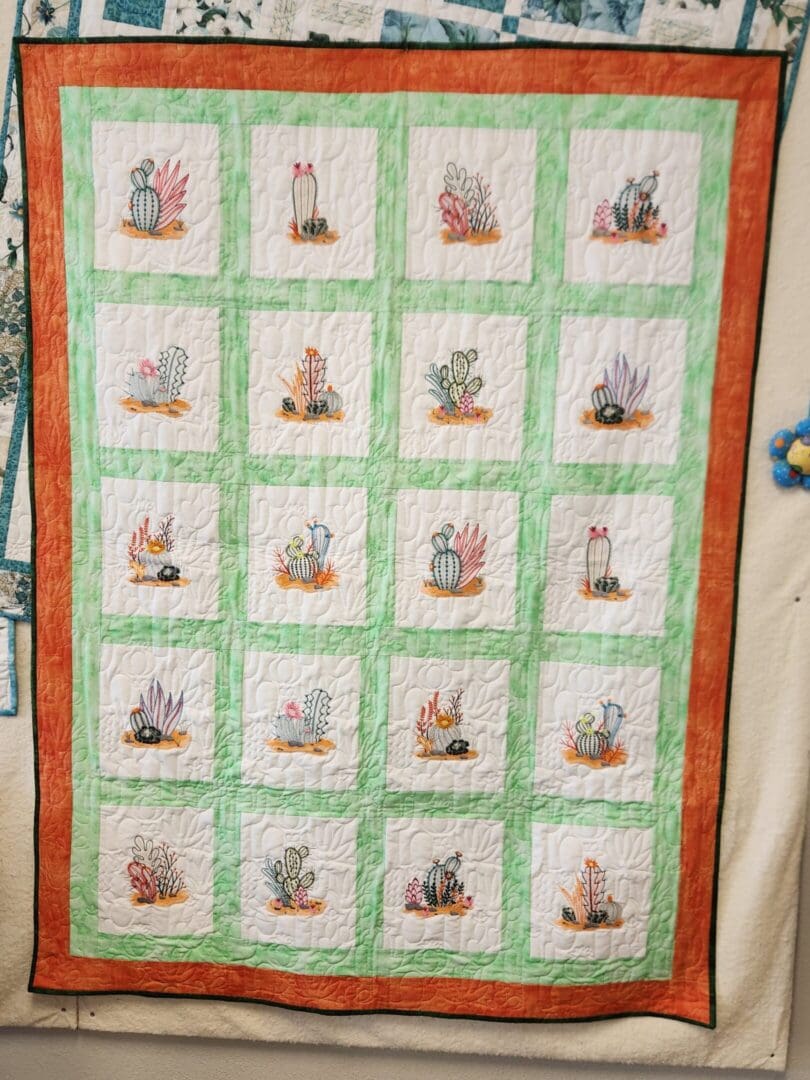 A quilt with bunny illustrations framed in green and orange borders.
