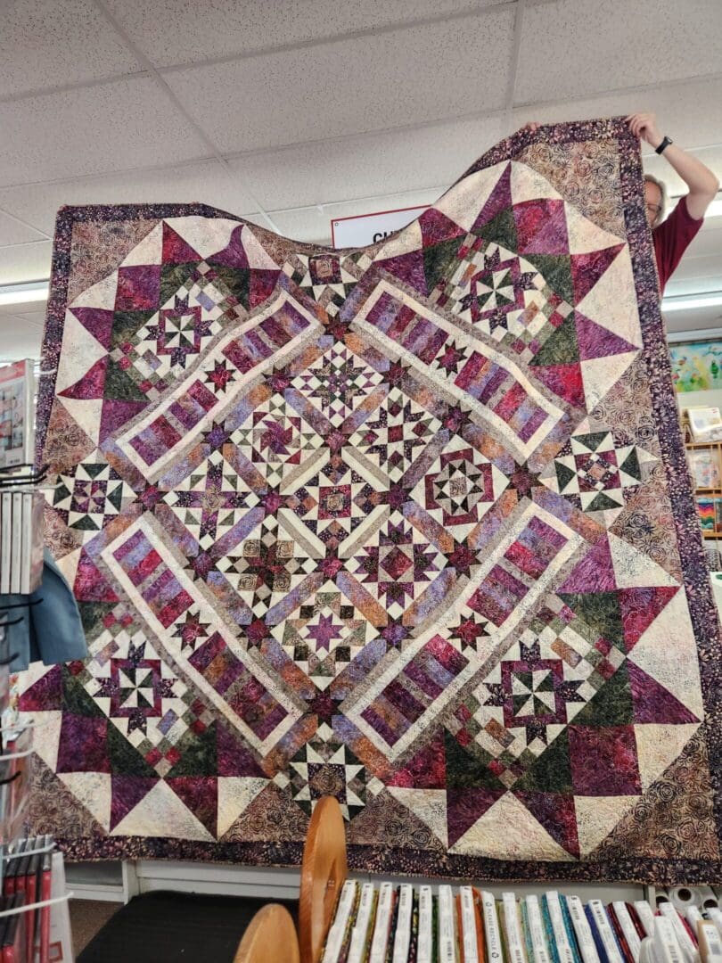 A detailed quilt with star and diamond patterns in earthy tones.