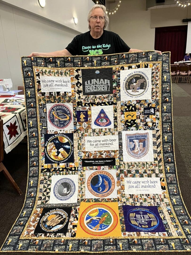 A person holding a detailed quilt with various embroidered patches.